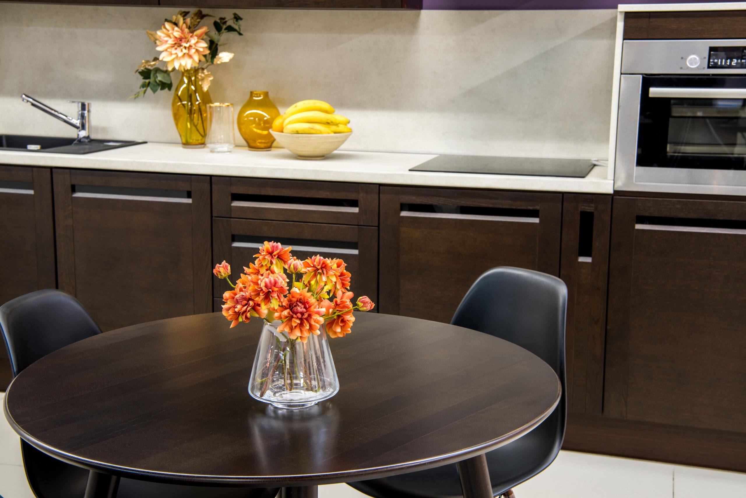 A modern kitchen with dark wood cabinets and dining table.